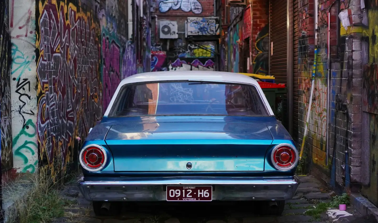 A classic Ford Falcon on Victorian club plates parked in a Melbourne laneway
